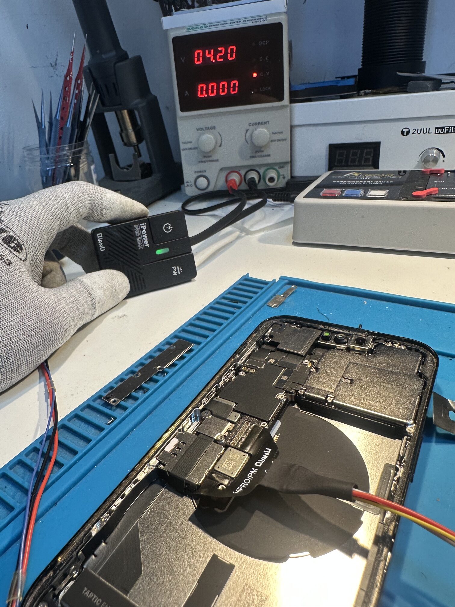 iPhone 14 Pro podłączony do zasilacza laboratoryjnego podczas kontroli poboru prądu w stanie wyłączenia